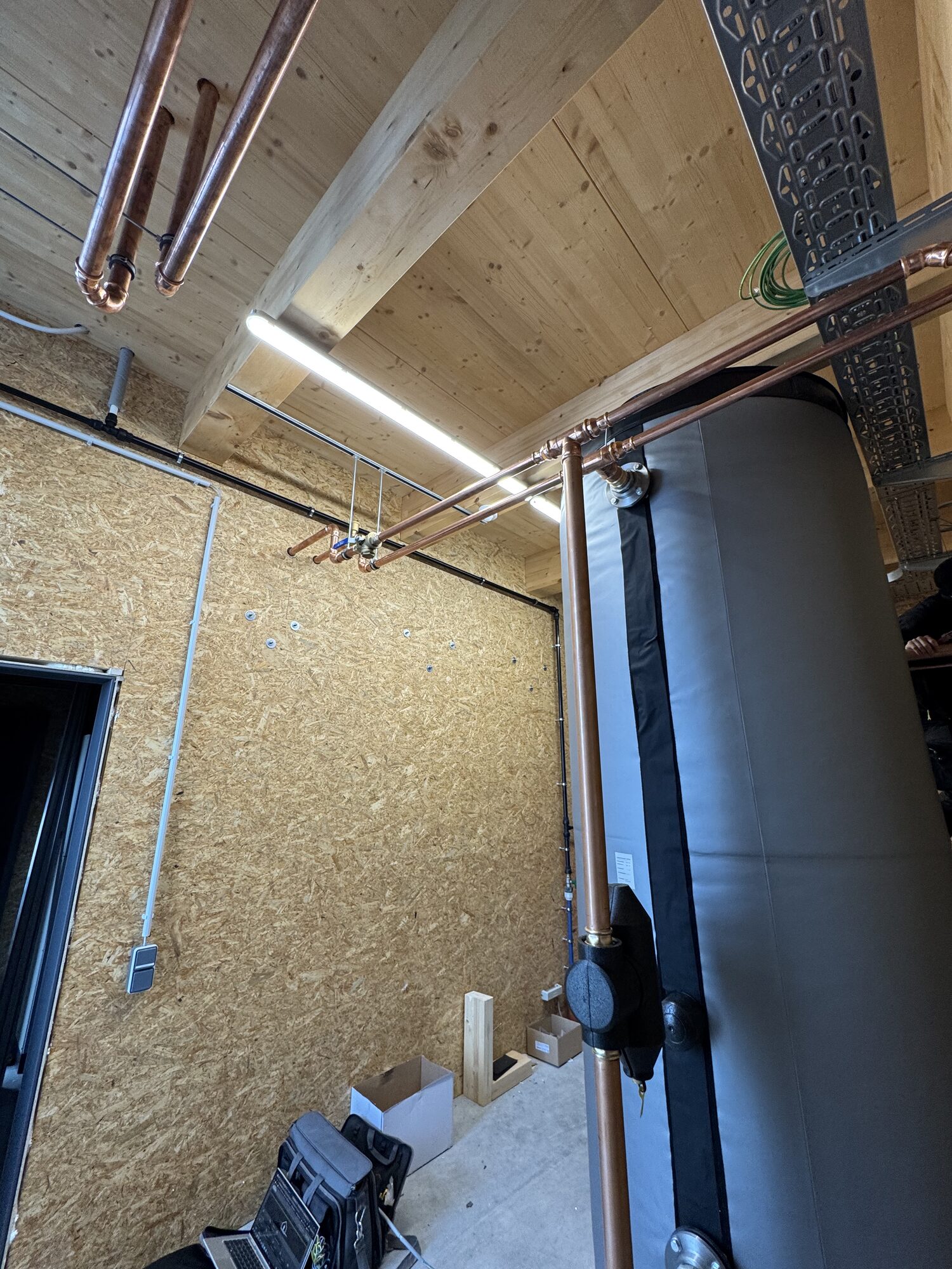 Pufferspeicher mit isolierter Kupferanbindung und Umwälzpumpe im Holzbau-Technikraum
