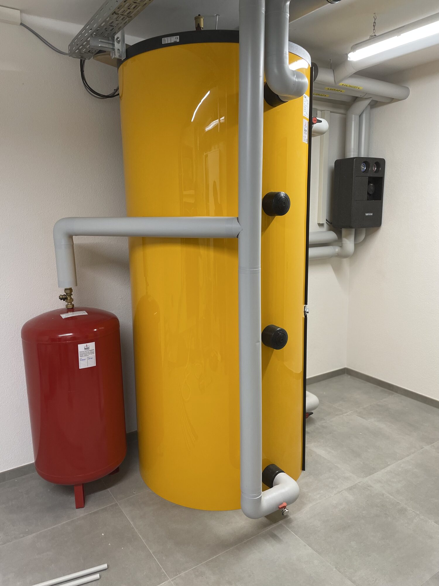 Pufferspeicher mit rotem Ausdehnungsgefäß und Heizkreisstation im Technikraum
