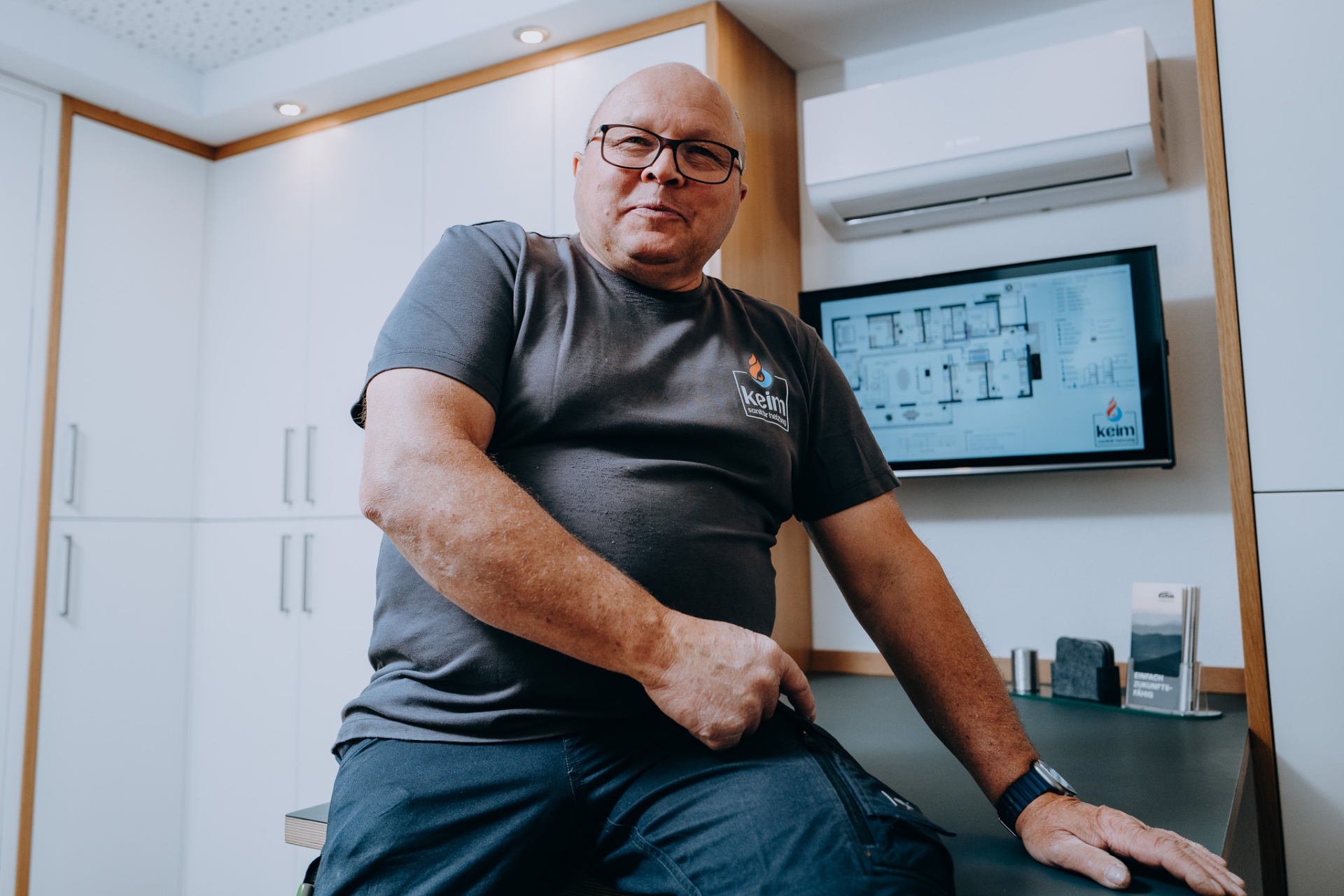Alfred Keim, ruhig im Gespräch, vor dem digitalen Leitungsplan eines Einfamilienhauses.