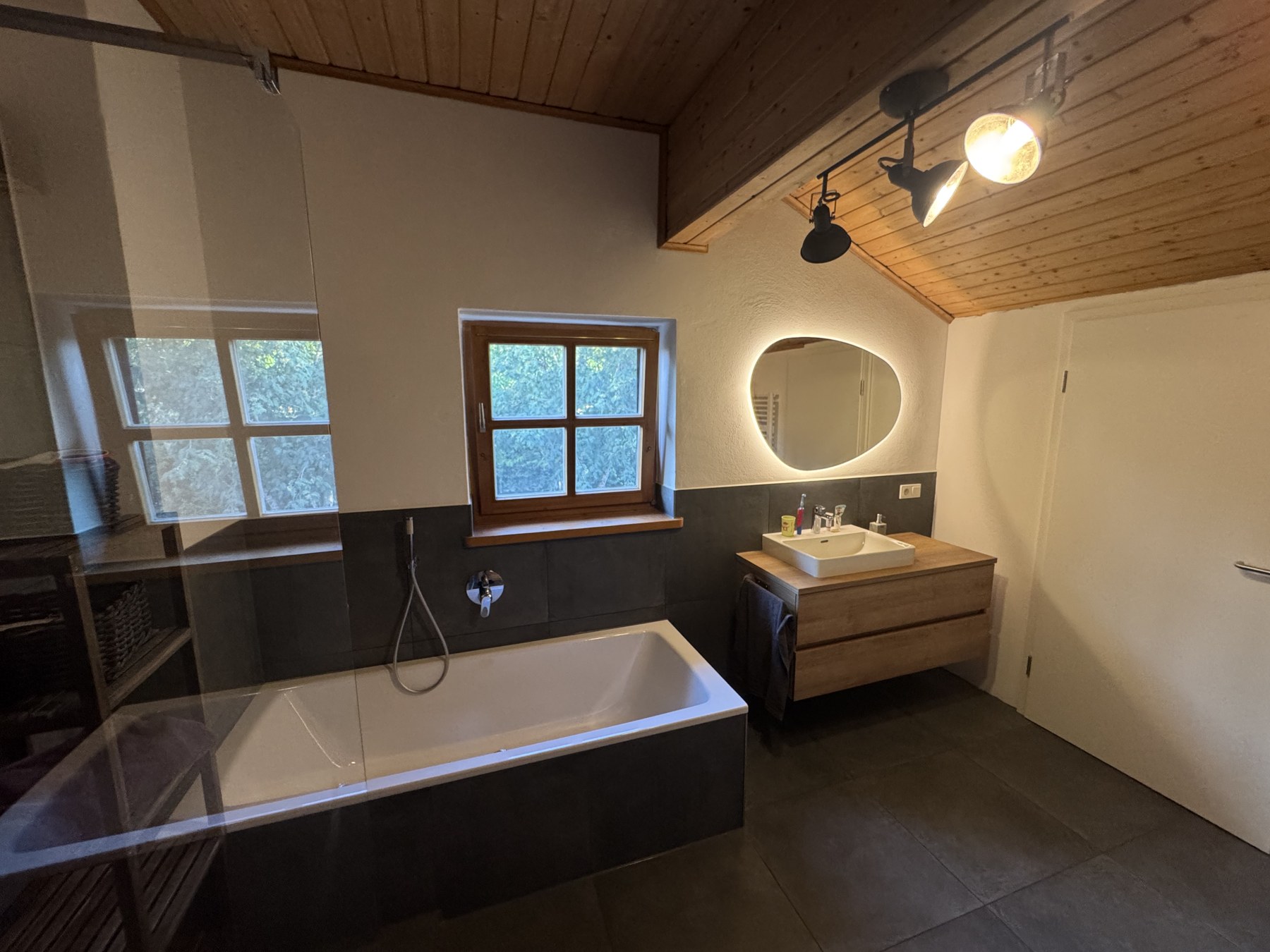 Blick ins fertige Dachbad mit großer Dusche, Badewanne und Waschtisch