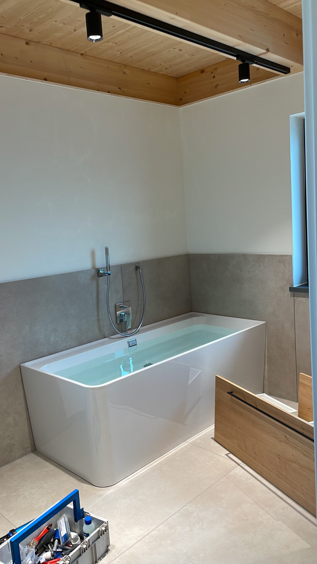 Elternbad mit freistehender Badewanne, Wandarmatur und Betonoptik-Fliesen