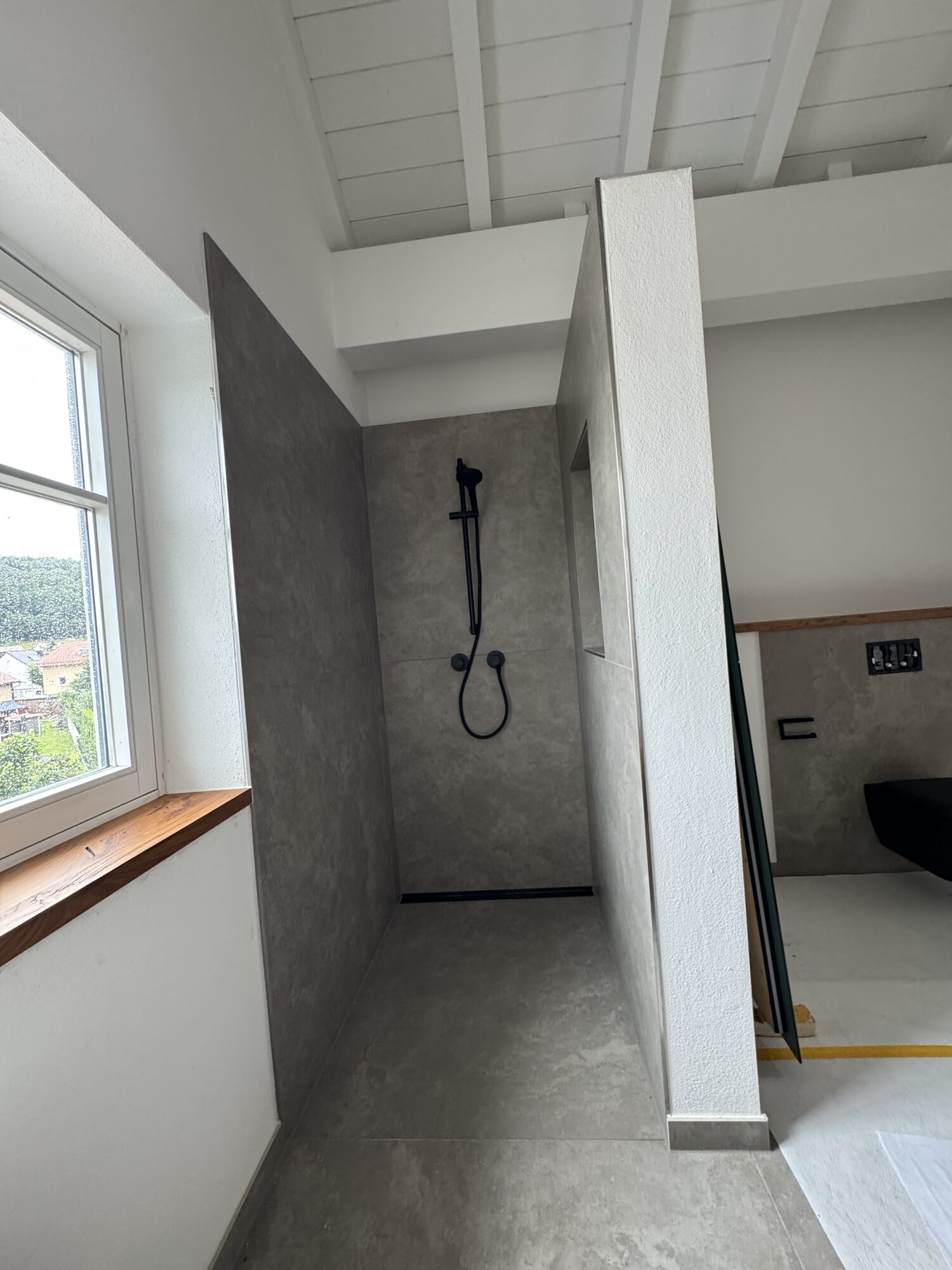 Bodengleiche Dusche unterm Dach mit schwarzer Armatur und Holzfensterbank
