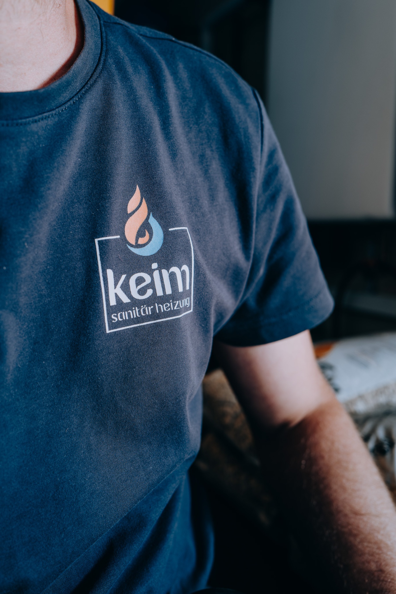 Nahaufnahme des keim-Shirts mit Firmenlogo auf der Brust eines Mitarbeiters.