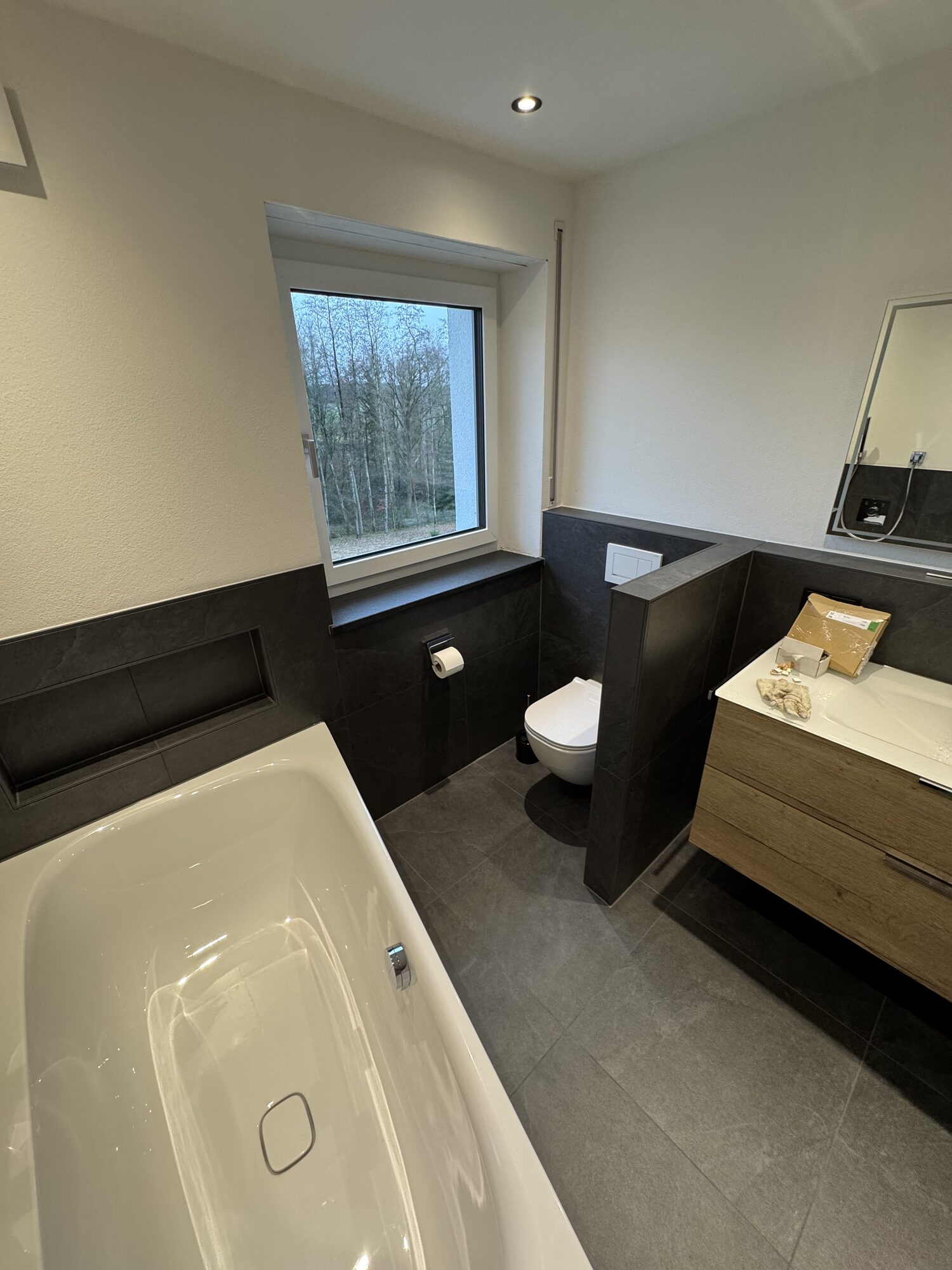 Hauptbad im Obergeschoss mit Badewanne, Wand-WC und Waschtisch in Holzoptik