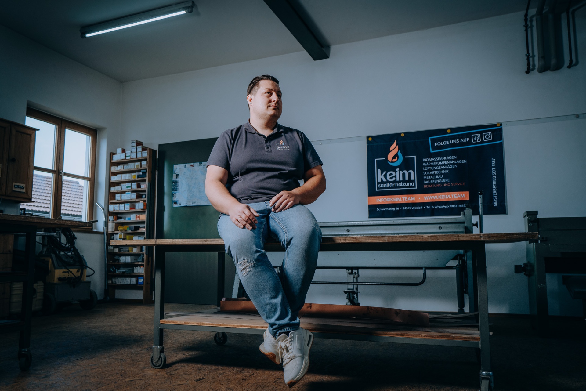 Christoph Keim in der Werkstatt, seitlicher Blick auf der Werkbank sitzend.