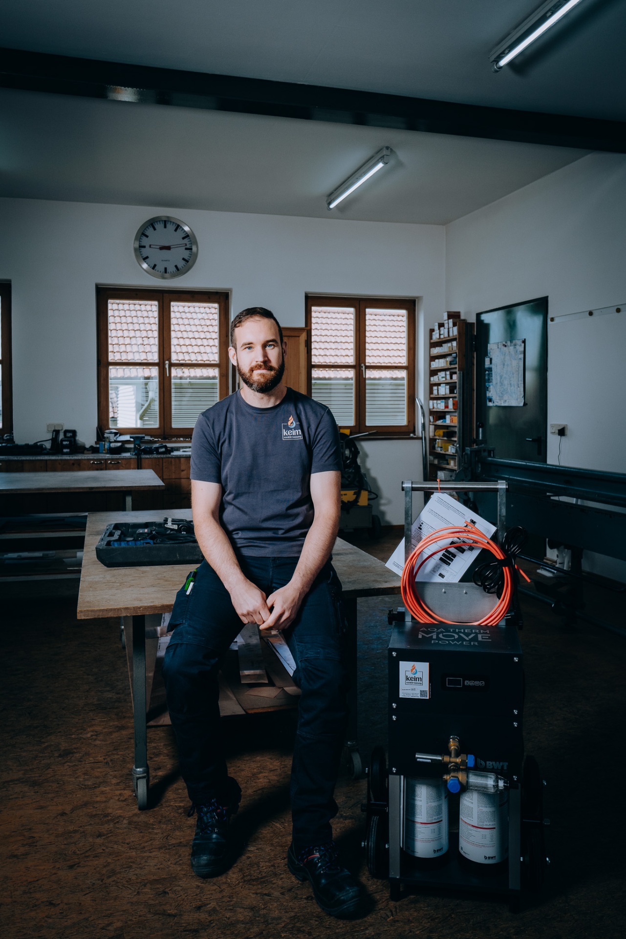 Christoph Keim sitzt auf der Werkbank neben der BWT AQA therm MOVE Power Spülanlage in der Werkstatt.