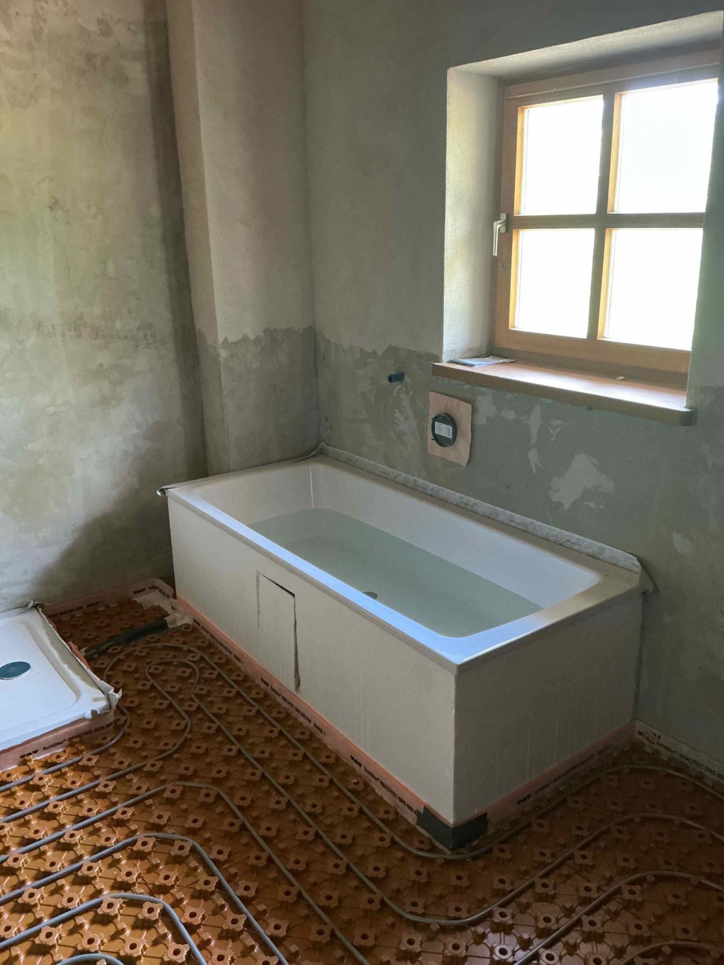 Badewanne auf Wannenträger vor dem Fenster, Fußbodenheizung fertig verlegt
