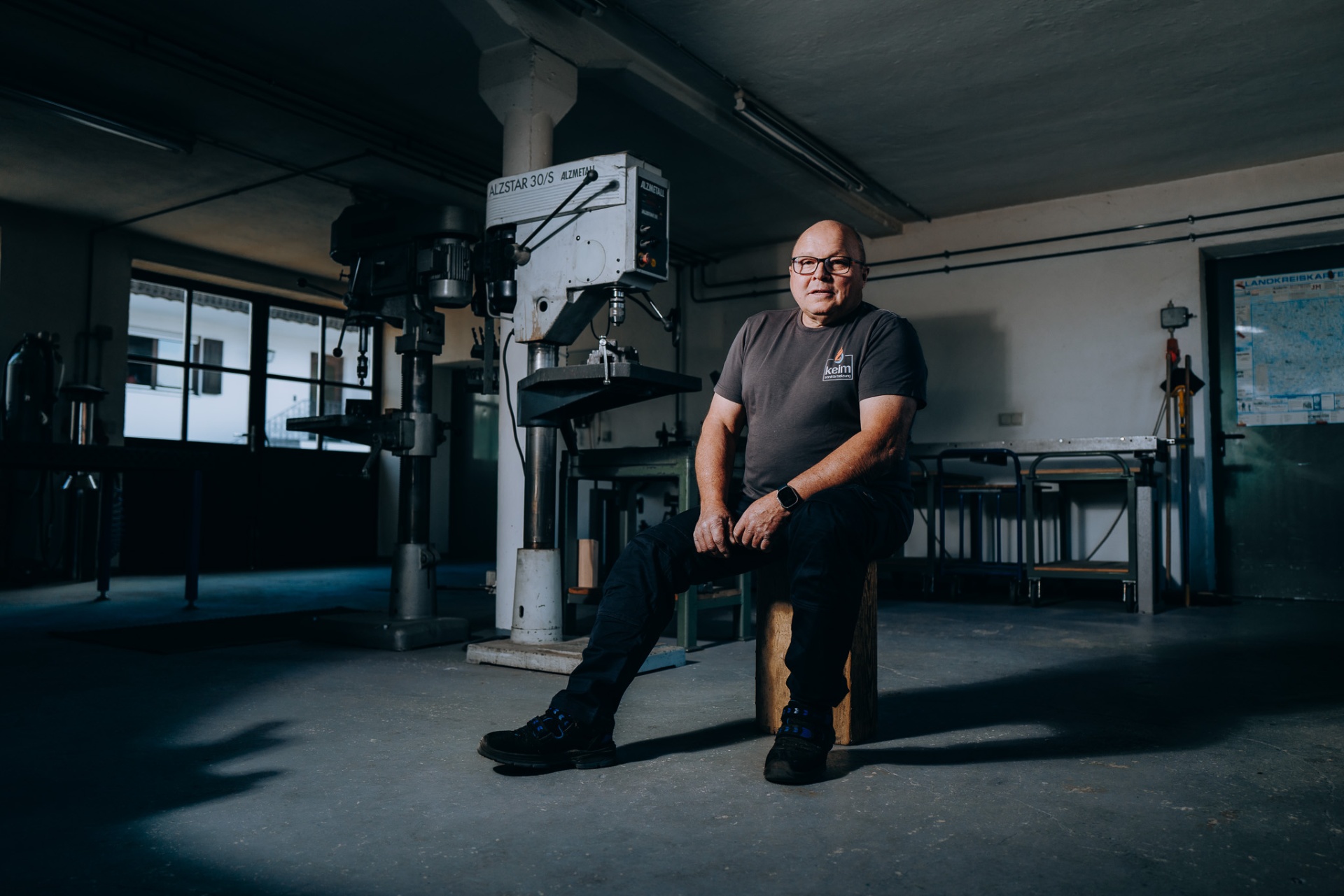 Senior-Chef von keim in der weiten Spenglerei-Werkstatt vor der großen Ständerbohrmaschine.