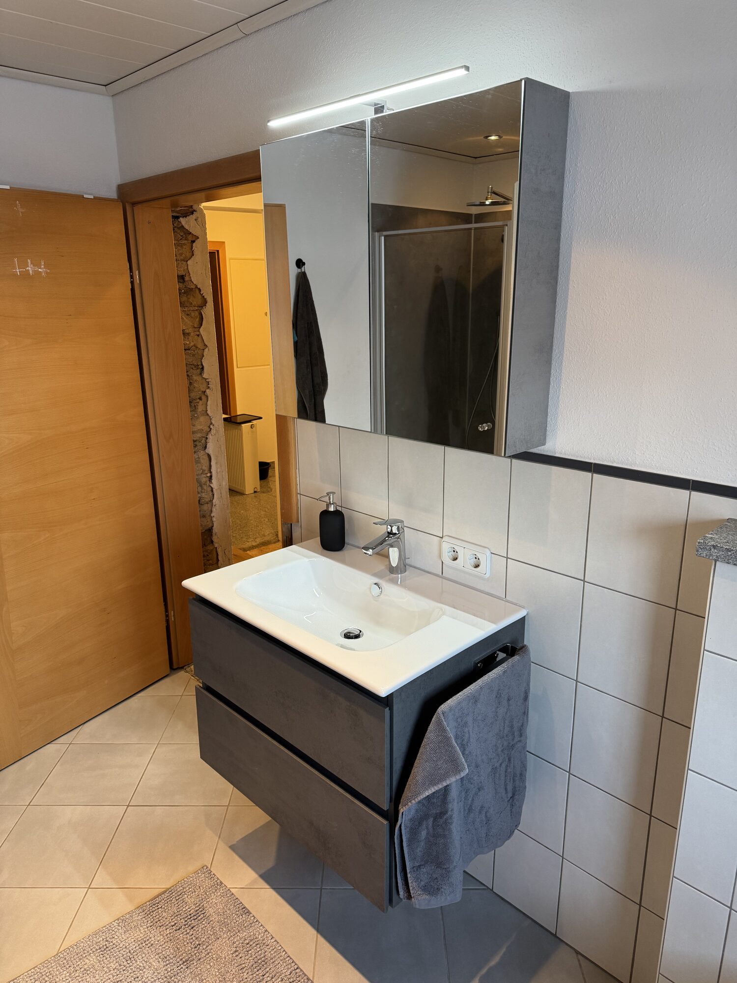 Neuer Waschtisch mit Unterschrank und beleuchtetem Spiegelschrank im Bestandsbad